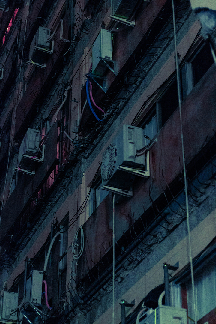 Zoom-in to a facade with wooden boards over windows and an array of air conditioning units.